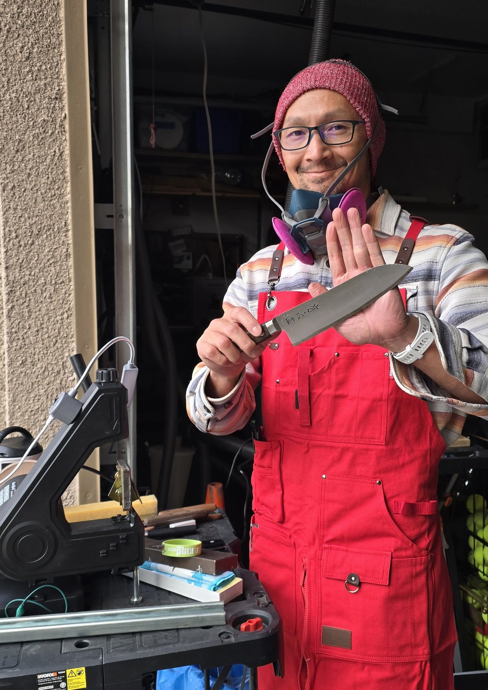 George holding up a sharpened knife in his workshop